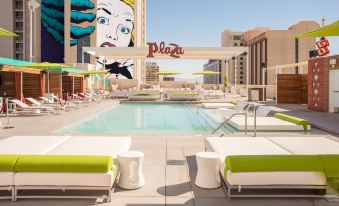 a modern outdoor pool area with a mural on the side and lounge chairs , under a clear blue sky at Plaza Hotel & Casino