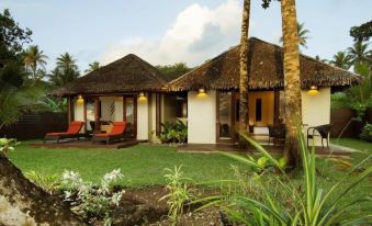 a small house surrounded by a lush green lawn , with palm trees in the background at Eratap Beach Resort