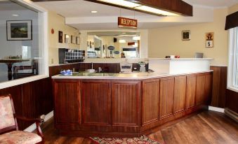 "a hotel reception area with wooden paneling , a counter , and a sign that says "" reception ""." at Auberge Gisele's Inn