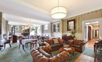 a spacious , well - decorated living room with brown leather couches , wooden furniture , and various dining tables at Hotel Etico at Mount Victoria Manor