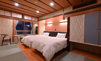 a modern bedroom with wooden walls , a large bed , and a window looking out to the city at Yamadaya