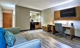 a modern hotel room with wooden floors , gray walls , and a desk area equipped with a computer and other equipment at Courtyard Hampton Coliseum Central