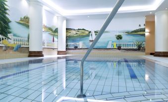 a large swimming pool with a mural of a lake and trees in the background at Novotel Freiburg am Konzerthaus