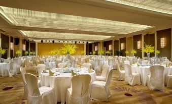 A ballroom is arranged for an event, with tables and chairs placed in the center at Expo Center Hotel