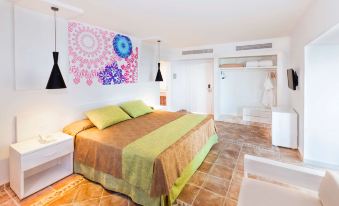 a large bed with a colorful blanket is in a room with a colorful wall hanging at Tryp Cayo Coco