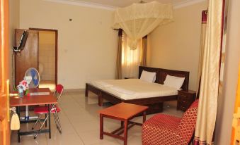 a spacious bedroom with a large bed , a dining table , and a chair in the room at Country Inn Masindi