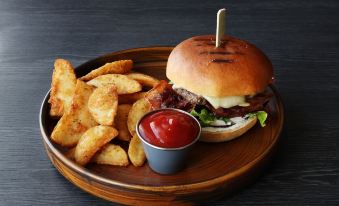 a wooden plate with a hamburger , fries , and ketchup on it , placed on a dining table at Fosshotel Westfjords