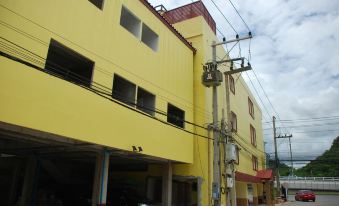 a yellow building with a car parked in front and power lines on the side at Sirasit 999 Mansion