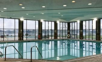a large indoor swimming pool with a glass wall , surrounded by windows that offer a view of the outdoors at Radisson Hotel Niagara Falls Grand Island
