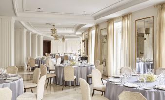 a large , elegant dining room with multiple tables and chairs set up for a formal event at Four Seasons Hotel Madrid