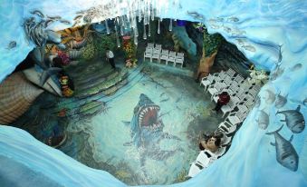 a large fish mural on the floor of a room , surrounded by chairs and tables at Crazy House