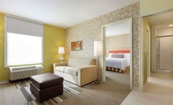 a living room with a couch , ottoman , and bed in front of a yellow wall at Home2 Suites by Hilton Canton