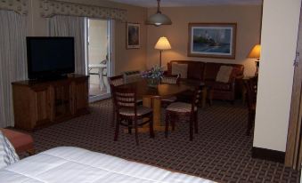 a hotel room with a bed , dining table , and chairs , as well as a television and lamps at Pinestead Reef Resort
