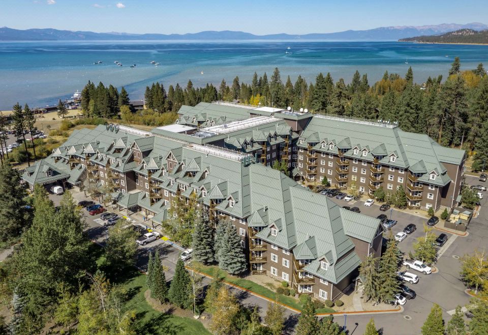 a large building with a green roof is surrounded by trees and overlooks the water at Hilton Vacation Club Lake Tahoe Resort South