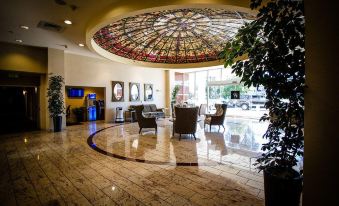 a lobby area with a large , colorful stained glass ceiling , marble floors , and several chairs at Grand Hotel