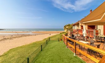 a large house with a wooden deck and patio furniture is situated on the beach at Hotel SanMar