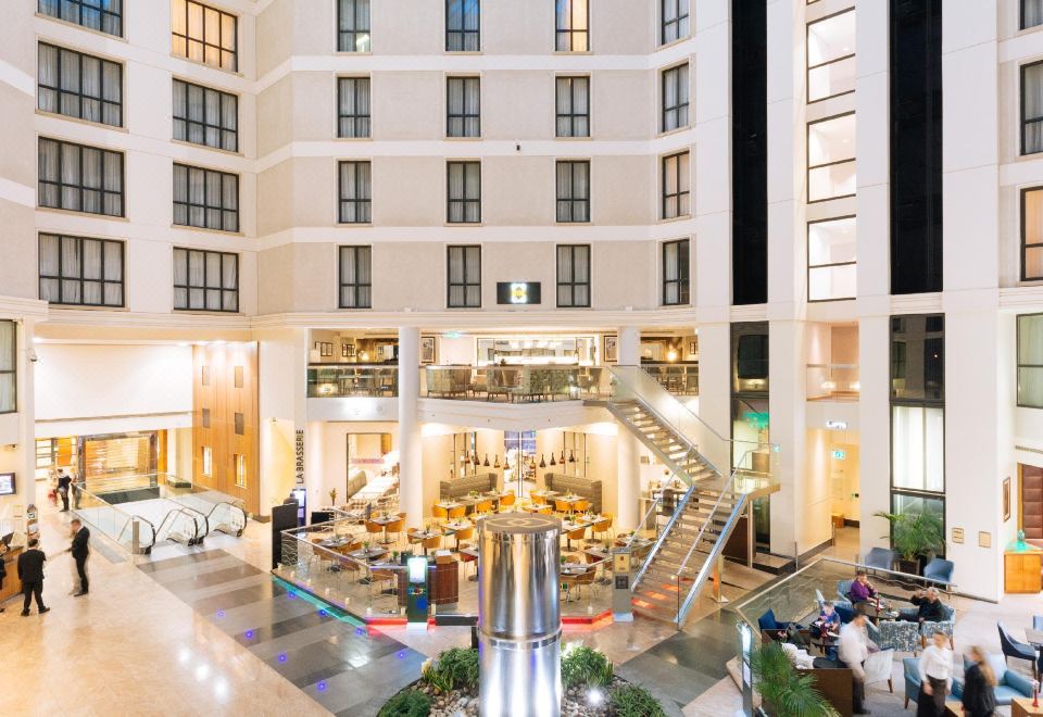 a large , modern hotel lobby with multiple floors and balconies , as well as various seating areas and decorative elements at Sofitel London Gatwick