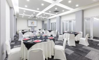"a large conference room with multiple round tables , chairs , and a screen displaying the words "" meeting room .""." at Hotel Frontera Clasico
