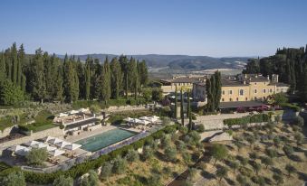 a large outdoor pool surrounded by lush green grass and trees , with a view of the surrounding landscape at Rosewood Castiglion del Bosco