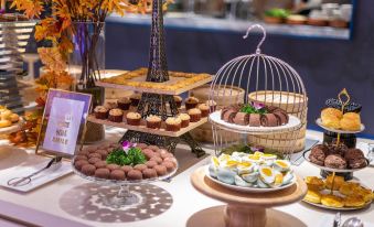 A table in the center with a variety of desserts, including small cakes and cookies at Crystal Orange Hotel（Shanghai Hongqiao Gubei Road）