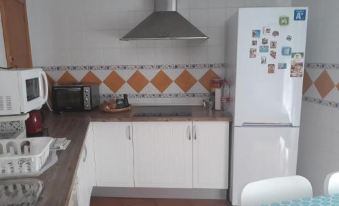a small kitchen with white appliances and orange and white tiled walls , equipped with a refrigerator , oven , microwave , and sink at Casa del Sol