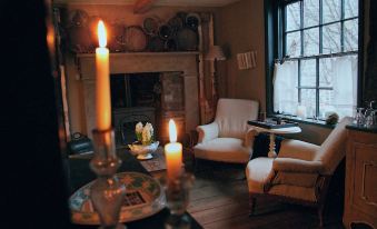 a cozy living room with two chairs , a fireplace , and a candle on the mantel at Radnor House