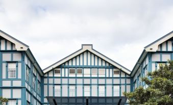 a large blue and white building with a covered entrance is surrounded by trees and clouds at Ovolo Woolloomooloo