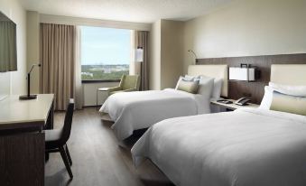 a hotel room with two beds , a desk , and a large window overlooking the city at Atlanta Airport Marriott