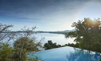a large , clear blue pool is surrounded by trees and overlooks a beautiful lake surrounded by mountains at Heritance Kandalama