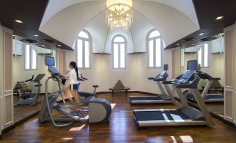 a woman is working out on a treadmill in a gym with various exercise equipment at Royal Rose Abu Dhabi