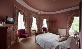 a luxurious bedroom with a large bed , two chairs , and a tv in the corner at Overwater Hall