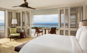 a luxurious bedroom with a view of the ocean , featuring a king - sized bed , a television , and a balcony at Four Seasons Resort Oahu at Ko Olina