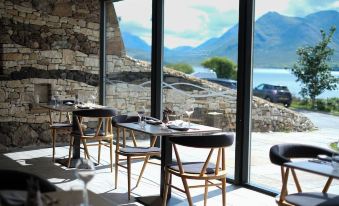 a dining room with a table and chairs set up for a meal , overlooking a beautiful mountain view at Isle of Raasay Distillery