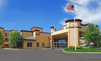 a large hotel with an american flag flying in front of it , surrounded by trees at Oxford Suites Pendleton