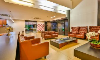 a modern , well - lit waiting room with multiple orange leather couches and chairs arranged in a lounge - like setting at San Marino Suites Hotel by Nobile