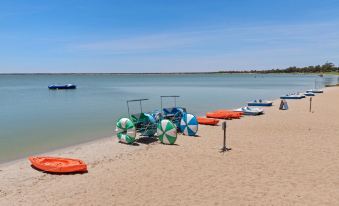 a sandy beach with several boats and umbrellas , providing a relaxing atmosphere for visitors to enjoy at Discovery Parks - Lake Bonney