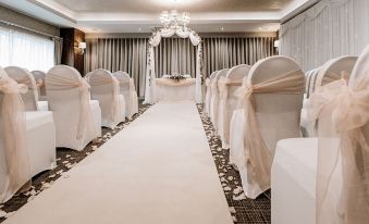 a wedding ceremony taking place in a room , with rows of white chairs arranged for guests at Horsley Lodge
