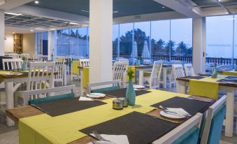 a large dining room with multiple tables and chairs arranged for a group of people to enjoy a meal at Sunset Beach Hotel