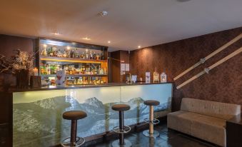 a well - equipped home bar with multiple chairs and stools , along with a wine bottle display at Luna Hotel Serra da Estrela