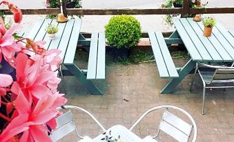 a patio with several wooden tables and chairs , along with potted plants and flowers , creating a pleasant outdoor space at The Horseshoe & Castle