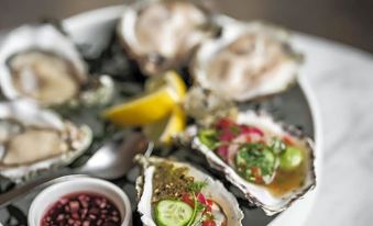 a white platter filled with oysters and various sauces , placed on a dining table in a restaurant at August