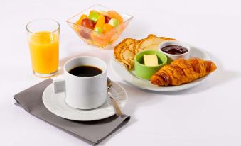 a table is set with a cup of coffee , croissants , and fruit , along with a glass of orange juice at Campanile Rouen Est - Franqueville Saint Pierre
