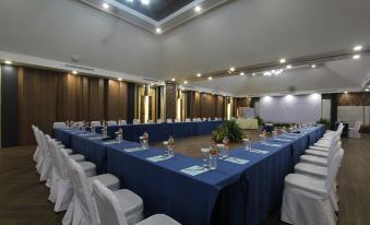 a large conference room with blue tables and white chairs is set up for a meeting at Holiday Resort Lombok