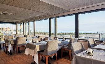 a dining room with a view of the ocean , featuring a table and chairs set up for a meal at La Cremaillere