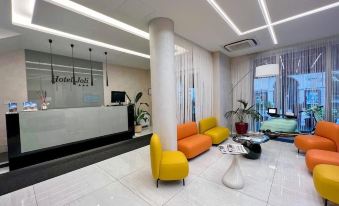 a modern and stylish lobby with white walls , yellow and orange chairs , and a reception desk at Hotel Joli