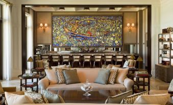 a large , colorful mural is displayed in the background of a room with two couches and chairs at The St. Regis Bahia Beach Resort, Puerto Rico