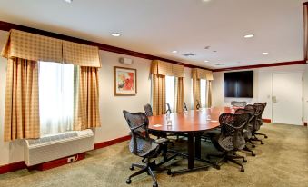 a conference room with a round table , multiple chairs , and a television mounted on the wall at Homewood Suites by Hilton Stratford