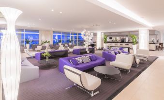 a modern lounge area with purple and white furniture , including couches , chairs , and a dining table at Amfora Hvar Grand Beach Resort