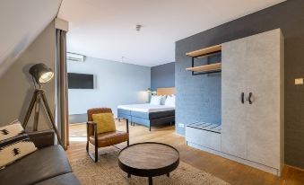 a modern bedroom with a comfortable bed , a chair , and a tv . also a closet in the room at Leonardo Hotel Lelystad City Center