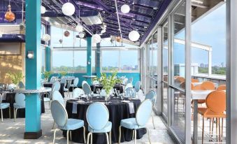 a restaurant with blue and black chairs , tables , and a large window overlooking the city at The Moonrise Hotel